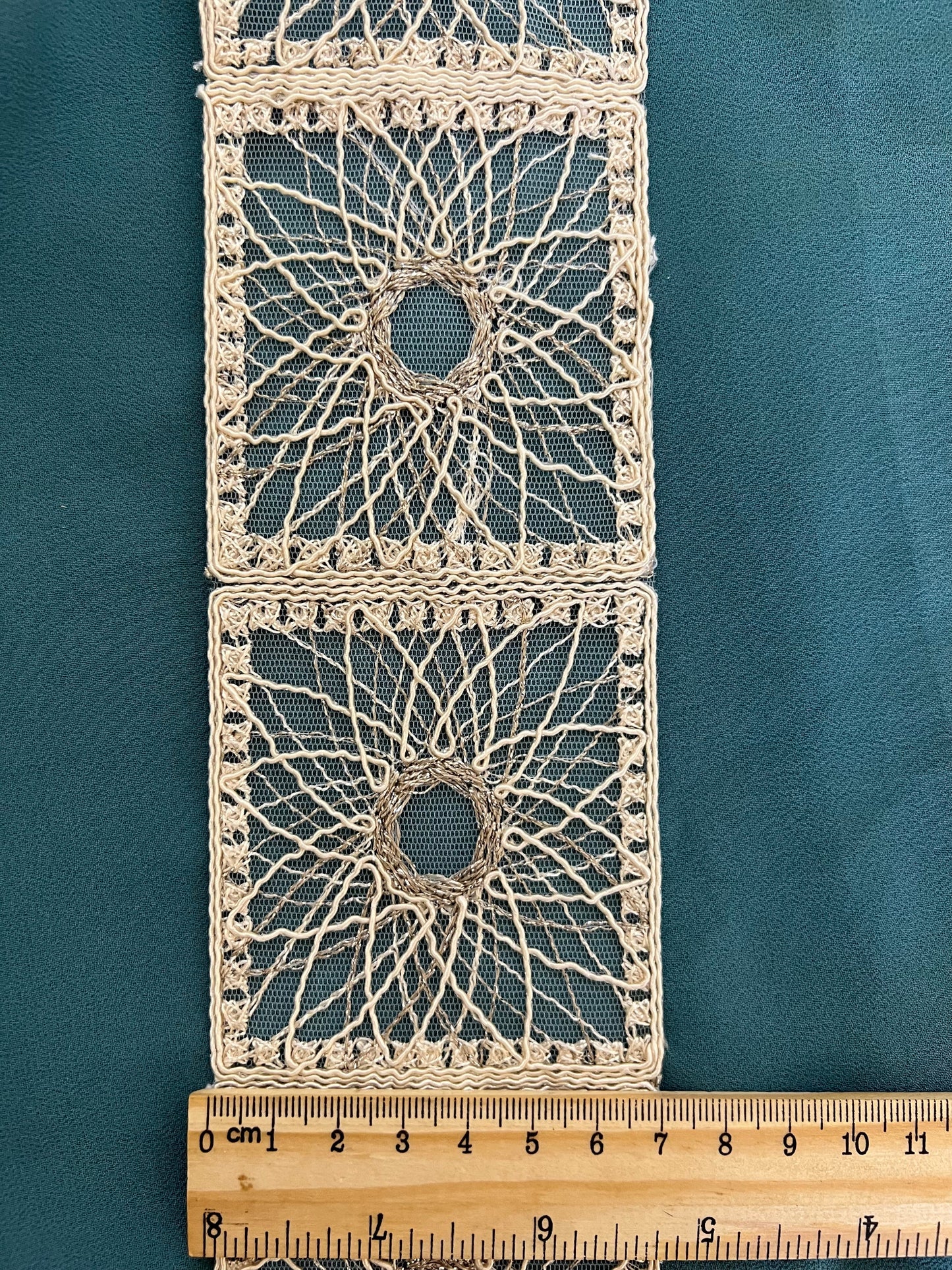 Galon type dentelle à motifs géométriques carrés et rosaces.