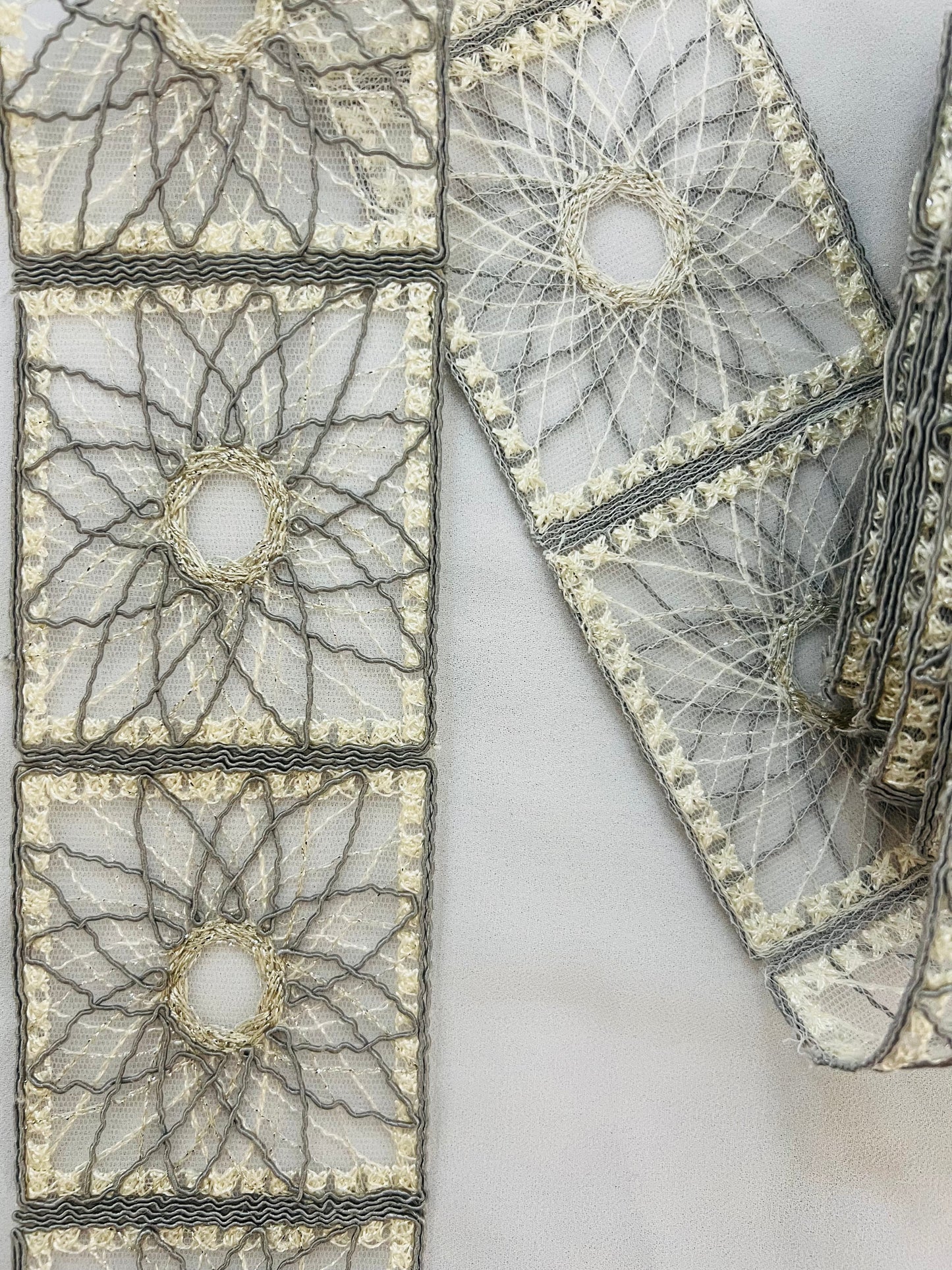 Galon type dentelle à motifs géométriques carrés et rosaces.