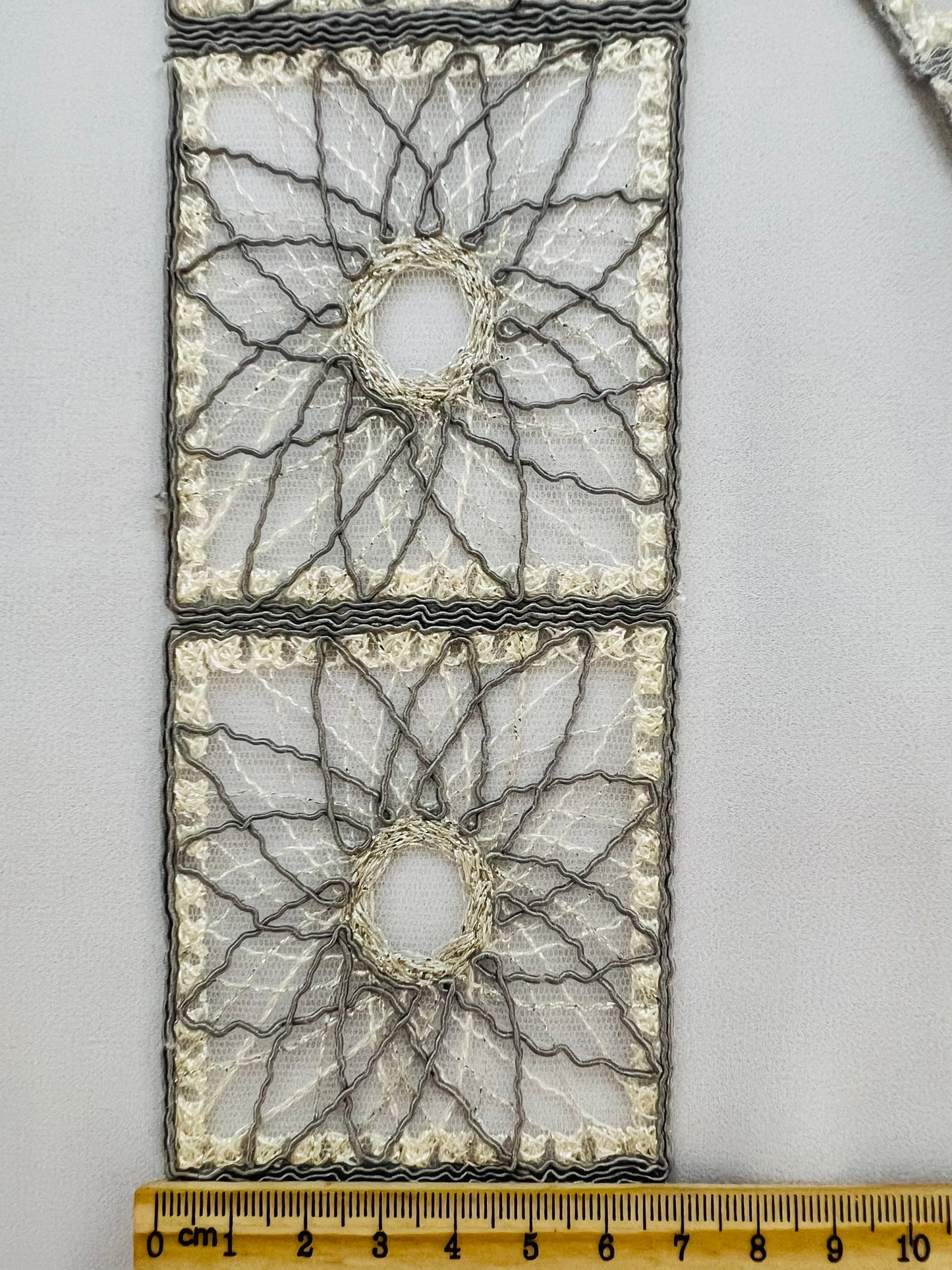 Galon type dentelle à motifs géométriques carrés et rosaces.
