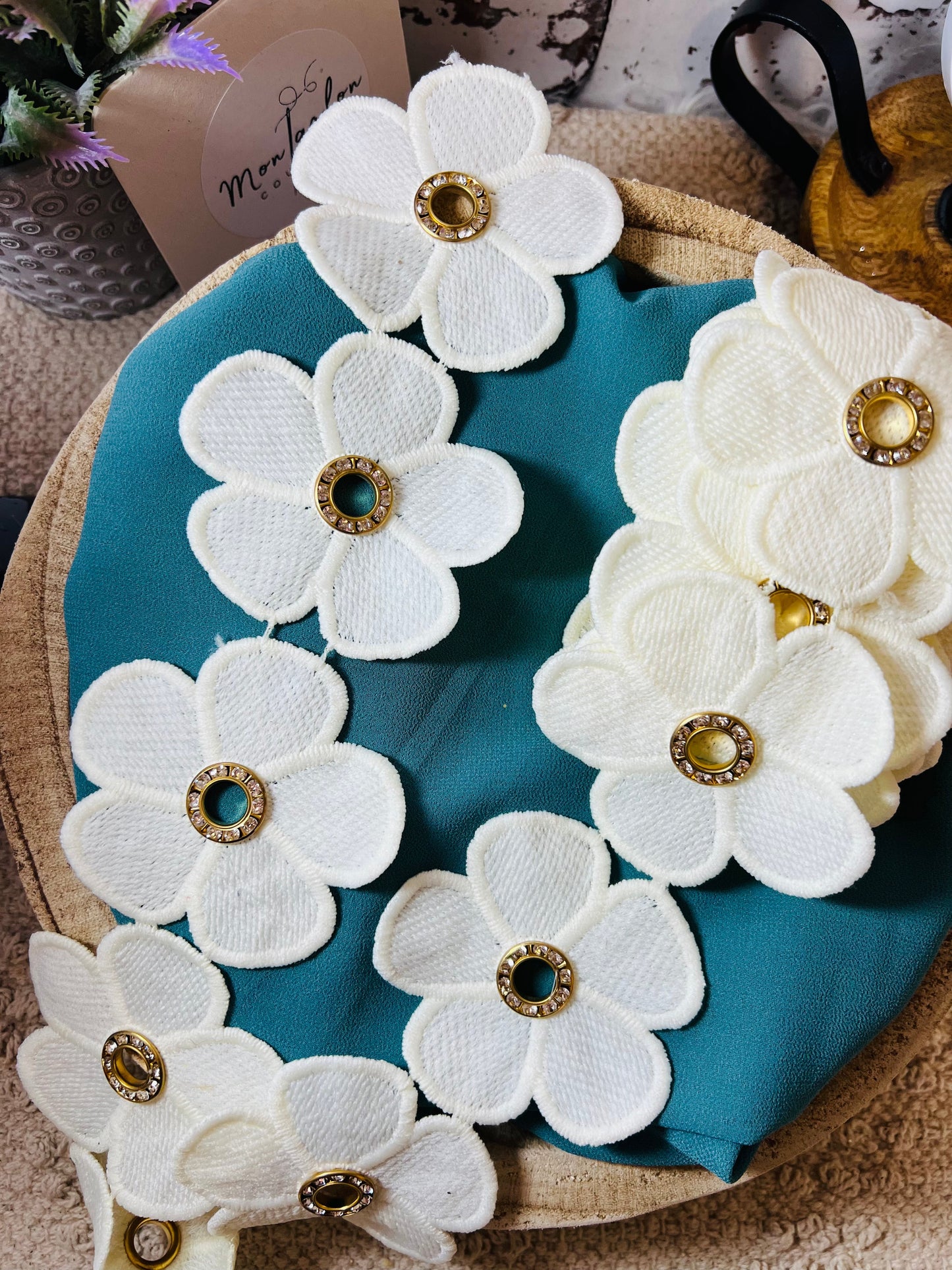 Galon blanc cassé de fleurs percées d'un anneau métallique de strass