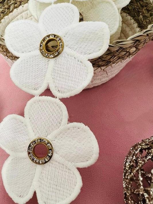 Galon blanc cassé de fleurs percées d'un anneau métallique de strass